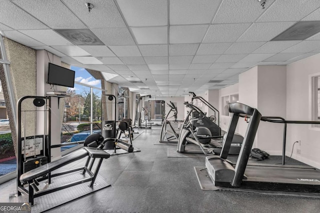 exercise room with baseboards and a drop ceiling