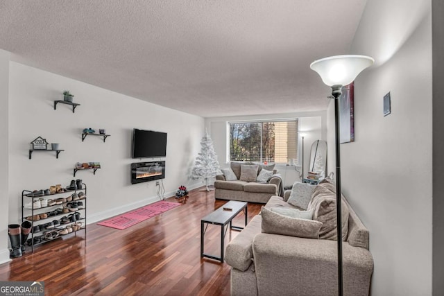 living room with a glass covered fireplace, wood finished floors, baseboards, and a textured ceiling