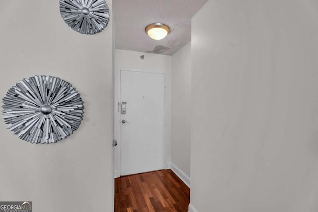 doorway to outside featuring baseboards, a textured ceiling, and wood finished floors