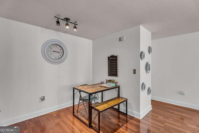 dining area featuring wood finished floors, baseboards, and a textured ceiling