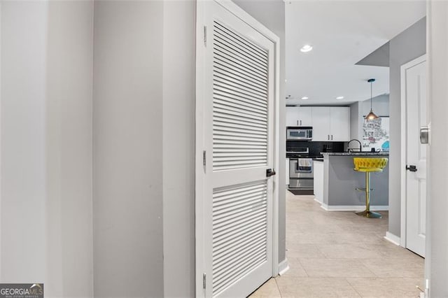 hall with recessed lighting and a sink