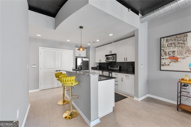 250 Pharr Rd Unit 1702, Atlanta, GA 30305 - kitchen with appliances with stainless steel finishes, white cabinetry, a kitchen bar, a center island with sink, and hanging light fixtures