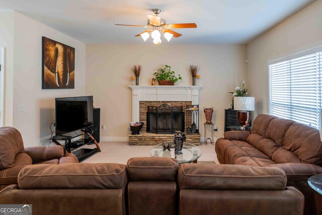 living room featuring baseboards, carpet flooring, a stone fireplace, and ceiling fan