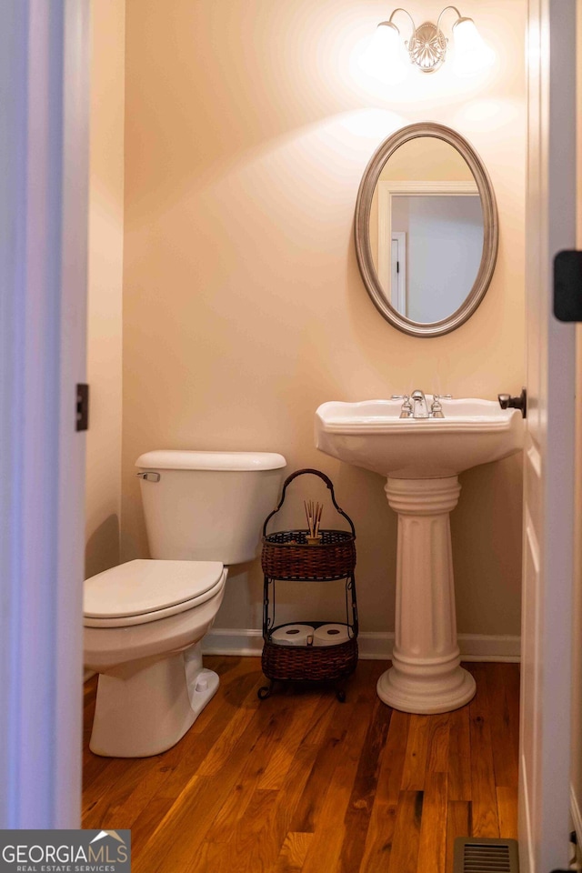 bathroom with toilet, wood finished floors, visible vents, and baseboards