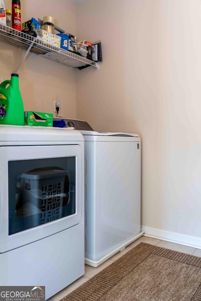 laundry room featuring tile patterned floors, laundry area, baseboards, and separate washer and dryer