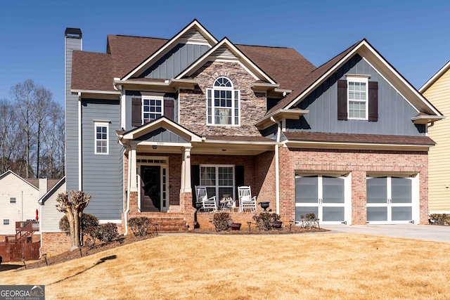 craftsman inspired home with board and batten siding, a front lawn, covered porch, driveway, and an attached garage