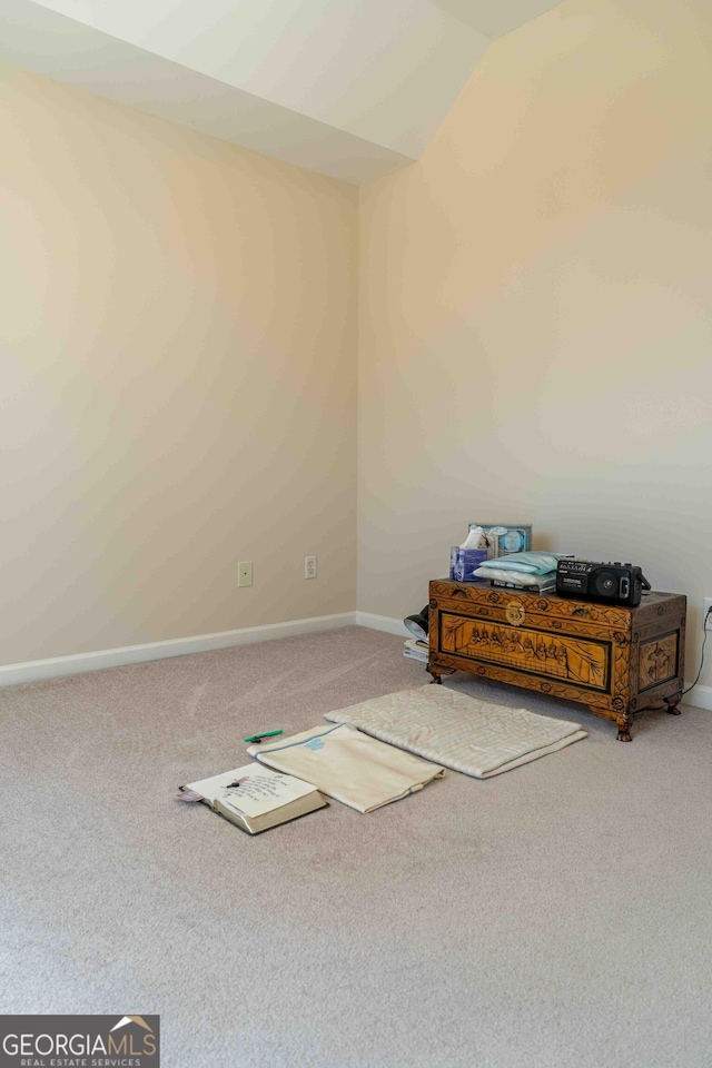 unfurnished room with baseboards, lofted ceiling, and carpet