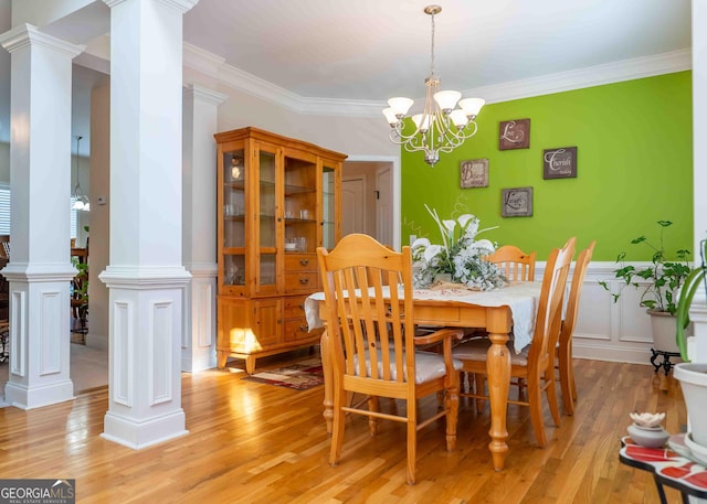 dining room with decorative columns, light wood-style floors, an inviting chandelier, and crown molding