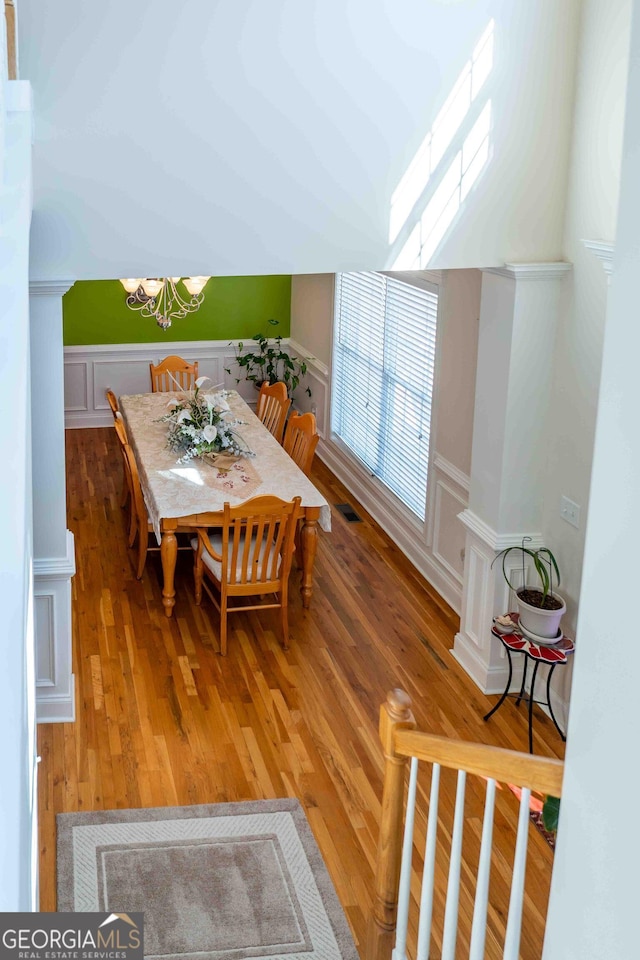 dining space featuring a decorative wall, visible vents, wainscoting, and light wood-type flooring