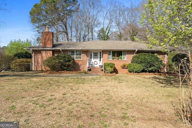 ranch-style home with brick siding, a chimney, and a front lawn