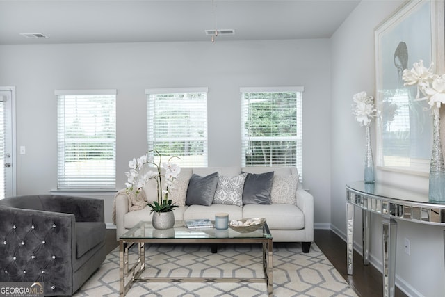 living area with visible vents, plenty of natural light, and wood finished floors