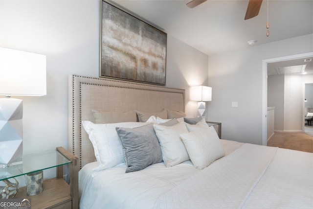 carpeted bedroom featuring attic access and a ceiling fan