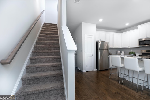 stairway with visible vents, recessed lighting, wood finished floors, and baseboards