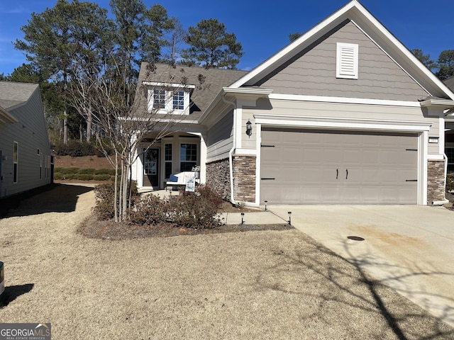 view of front of property featuring a garage, stone siding, and driveway