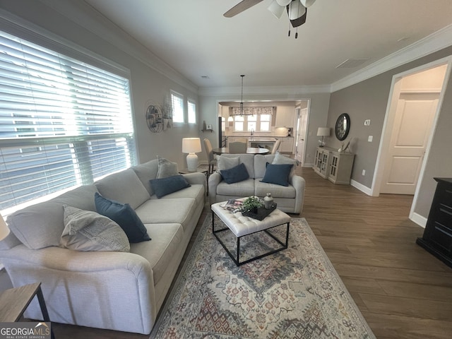 living area featuring baseboards, wood finished floors, a ceiling fan, and ornamental molding