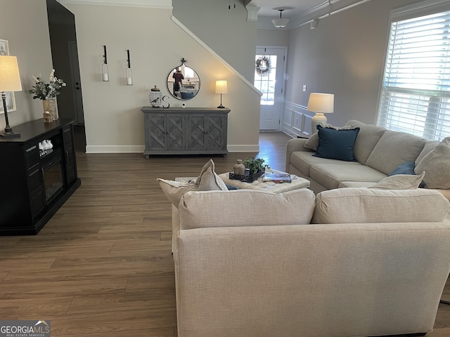 living area with wood finished floors, baseboards, and ornamental molding