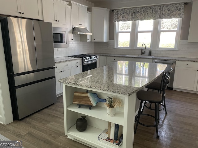 kitchen featuring a sink, open shelves, under cabinet range hood, appliances with stainless steel finishes, and dark wood-style flooring