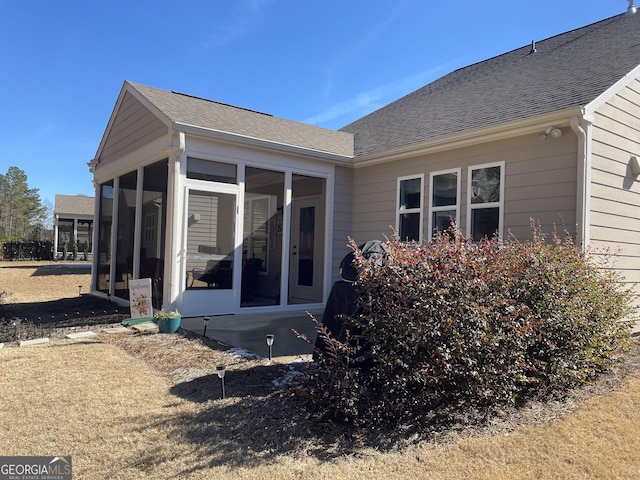 back of property with roof with shingles and a sunroom