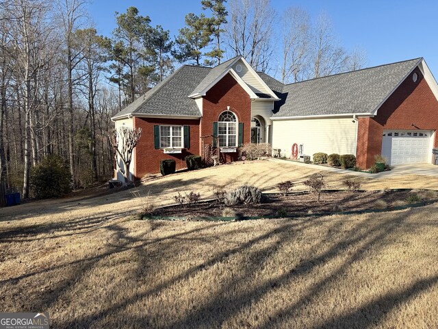 view of front facade featuring driveway, a front yard, brick siding, and an attached garage