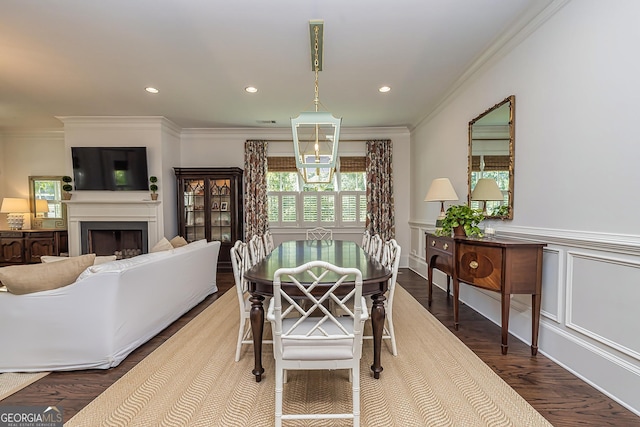 dining space with a wainscoted wall, wood finished floors, recessed lighting, a fireplace, and crown molding
