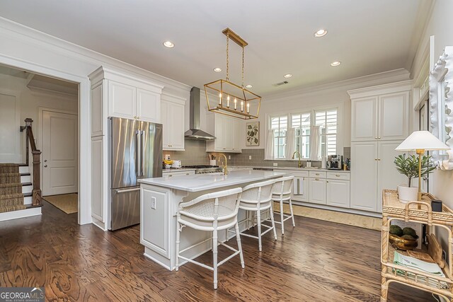 kitchen featuring white cabinets, wall chimney exhaust hood, crown molding, a chandelier, and high end refrigerator