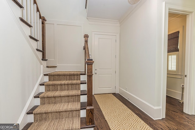 staircase with baseboards, wood finished floors, and ornamental molding