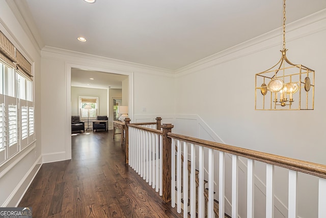 corridor with crown molding, dark wood finished floors, an upstairs landing, recessed lighting, and an inviting chandelier