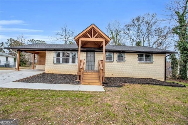 ranch-style house with brick siding, an attached carport, a front lawn, concrete driveway, and central AC unit