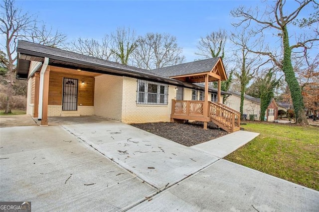 view of front of property with brick siding, an attached carport, driveway, and a front lawn