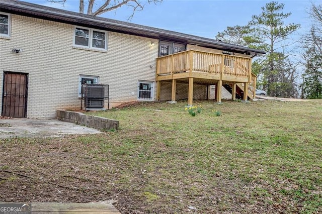 back of house featuring a yard, brick siding, a deck, and stairway