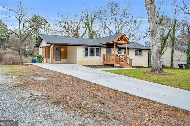 view of front of home featuring an attached carport, concrete driveway, brick siding, and a front yard