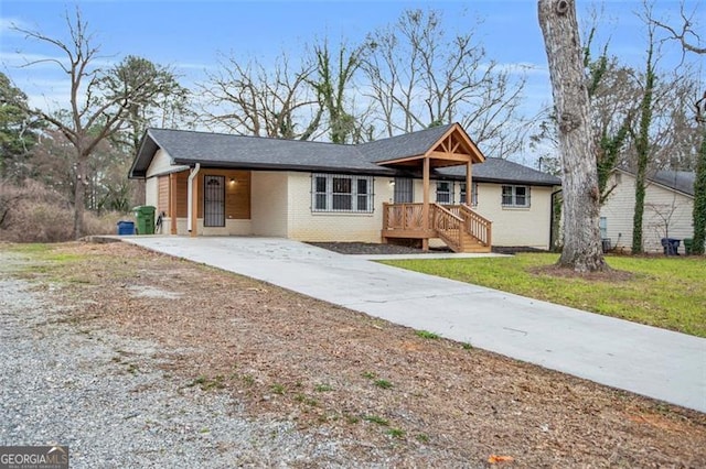 ranch-style home featuring a front yard, an attached carport, concrete driveway, and brick siding