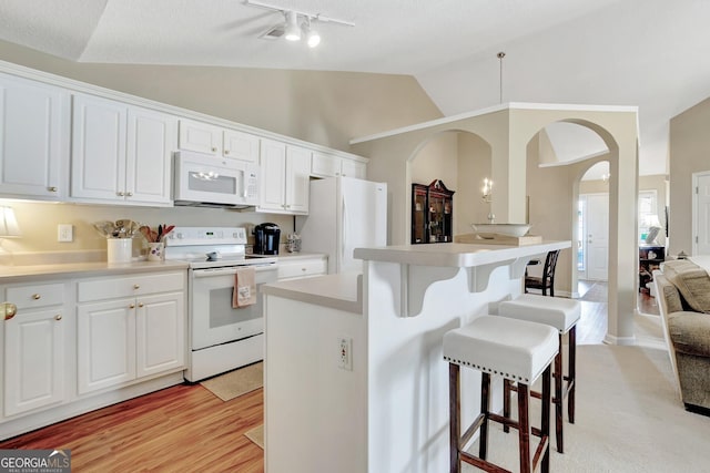 kitchen with white appliances, lofted ceiling, arched walkways, white cabinets, and a kitchen breakfast bar