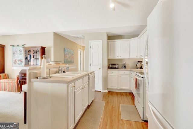 kitchen featuring a center island, light wood-style flooring, white cabinets, white appliances, and a sink