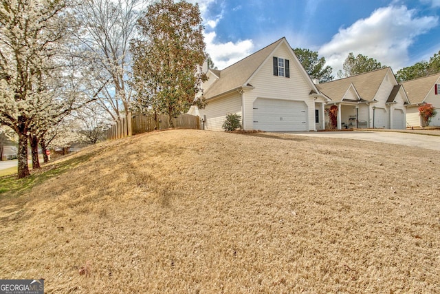 view of front of home featuring a front lawn, concrete driveway, a garage, and fence