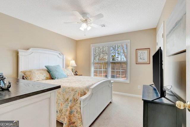 bedroom featuring a ceiling fan, baseboards, visible vents, a textured ceiling, and light carpet