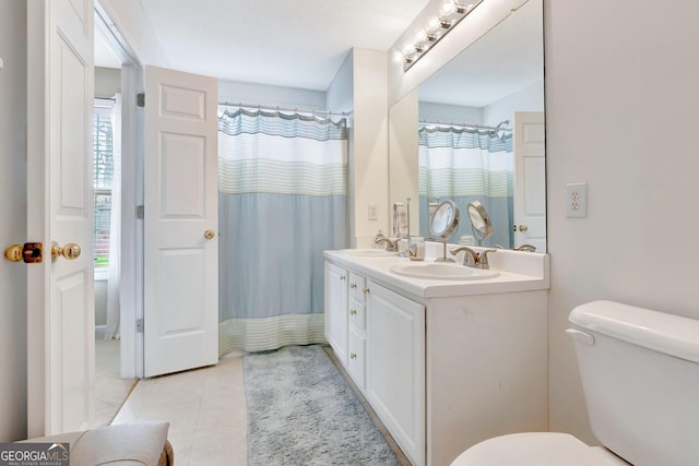 bathroom with a sink, toilet, double vanity, and tile patterned floors