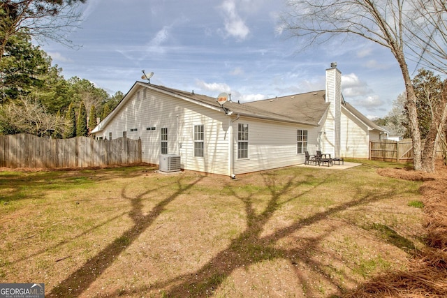 rear view of house with fence, cooling unit, a yard, a chimney, and a patio area