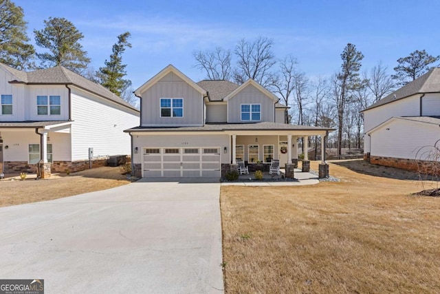 view of front of home featuring a front yard, a porch, an attached garage, concrete driveway, and board and batten siding