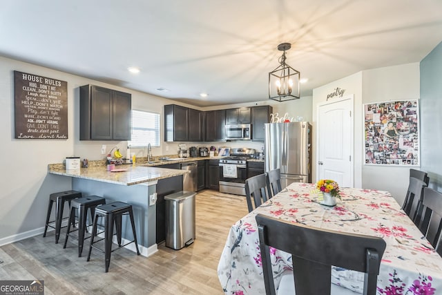 197 Stocks Cir, West Point, GA 31833 - kitchen featuring light stone counters, stainless steel appliances, light wood-style floors, a peninsula, and a kitchen bar