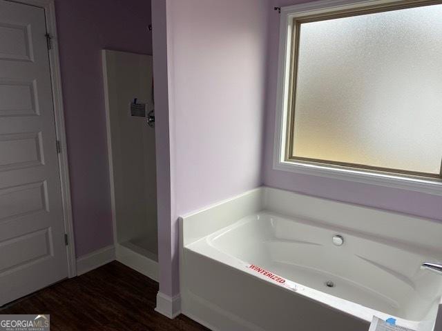 bathroom featuring a garden tub, wood finished floors, and a shower stall