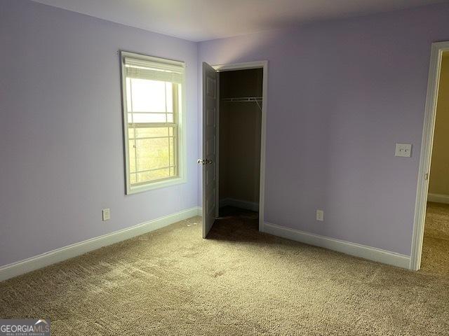 unfurnished bedroom with a closet, baseboards, and carpet