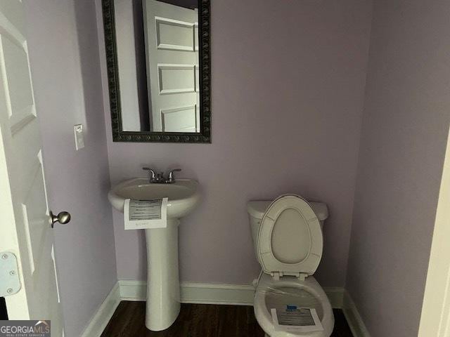 bathroom with toilet, wood finished floors, and baseboards