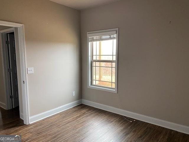 empty room featuring dark wood-type flooring and baseboards