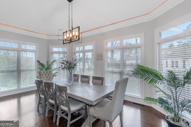 dining area with visible vents, dark wood-style floors, ornamental molding, and an inviting chandelier