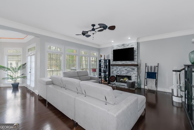 living area featuring dark wood-style floors, ornamental molding, a fireplace, and ceiling fan