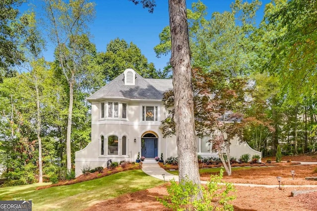 view of front of house with stucco siding and a front lawn