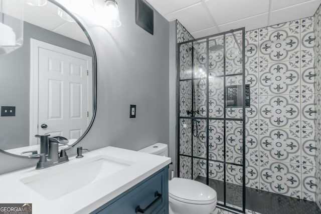 full bath featuring visible vents, a drop ceiling, toilet, tiled shower, and vanity