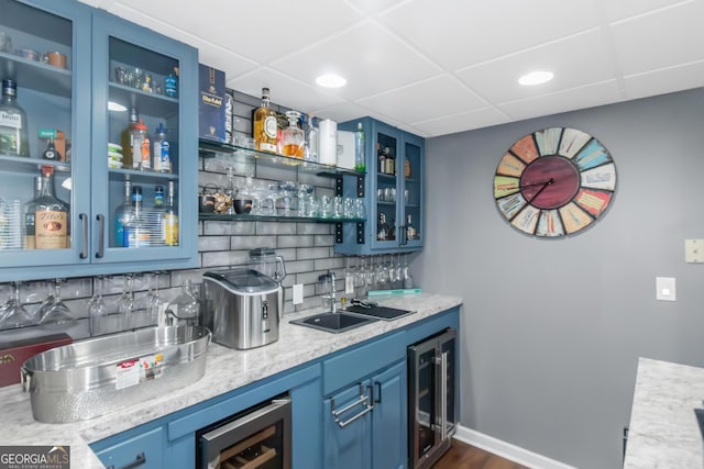 bar with wine cooler, decorative backsplash, wet bar, and a sink