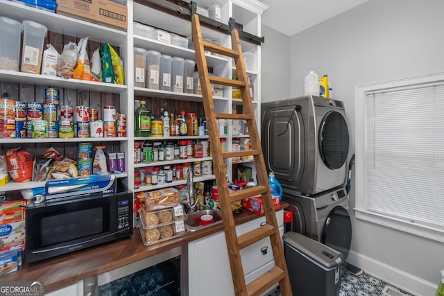 washroom featuring beverage cooler, laundry area, stacked washer and clothes dryer, and baseboards